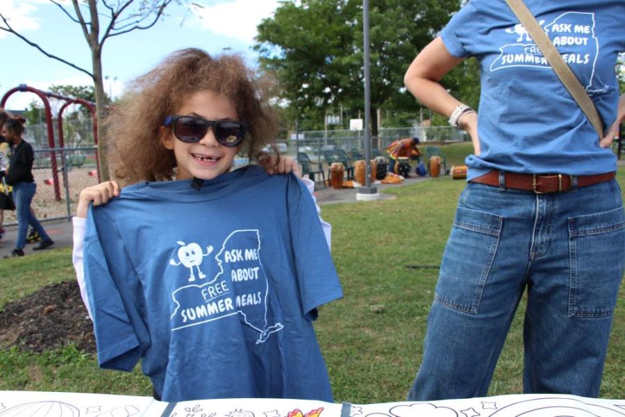 Girl holding Free Summer Meals Shirt