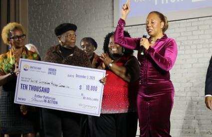 Live Limitless Power Pitch Winner pointing to sky with check behind her