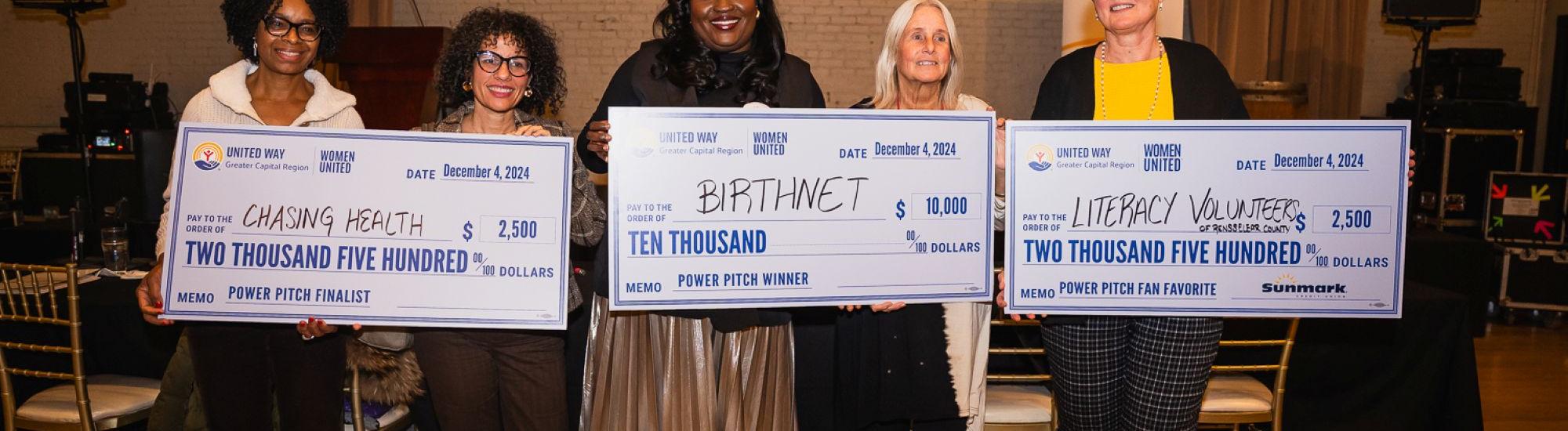 6 Women standing with 3 large checks after Power Pitch