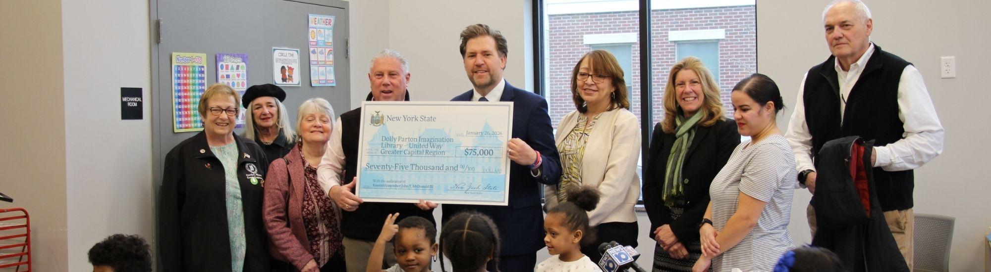 Group photo holding large check for $75K