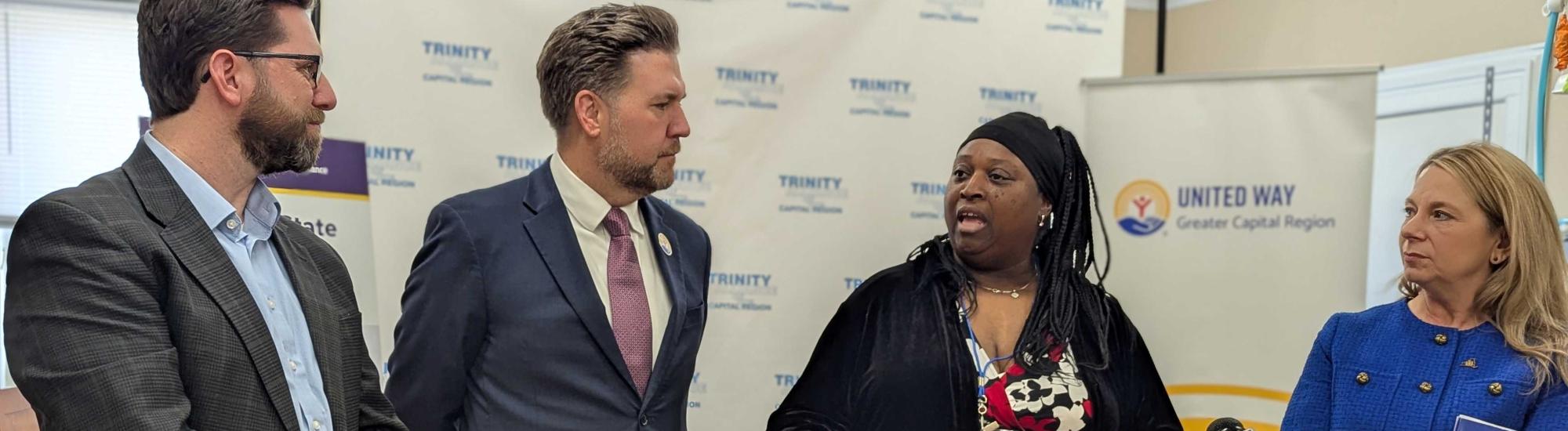 Women speaking at VITA Press conference, three people standing next to her