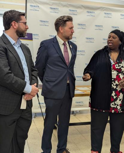 Women speaking at VITA Press conference, three people standing next to her
