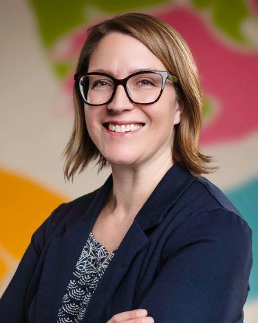 Melissa arms crossed smiling against colorful wall