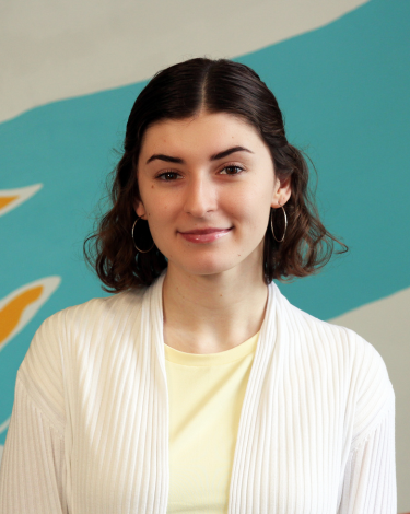 Vanessa smiling in white shirt against colorful wall