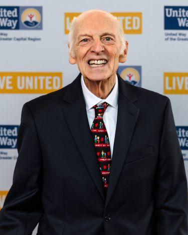 Brian Barr against UW backdrop in black blazer and teacher tie