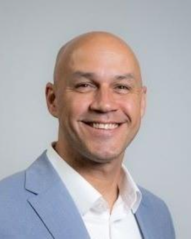 Brian smiling in light blue blazer and white shirt