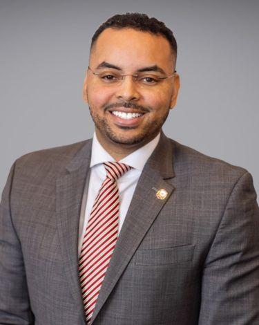 Michael-Aaron in gray with red and white stripe tie smiling